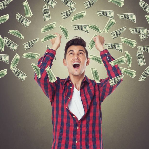 excited businessman looking up at raining dollar bills