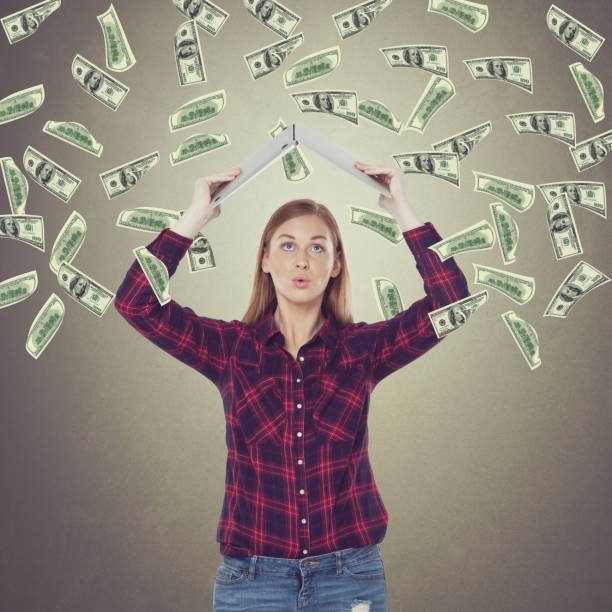 excited businesswoman holding laptop over her head with flying money